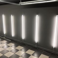 an empty room with several lights on the wall and checkered flooring in front of it