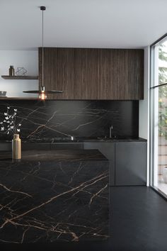 a kitchen with black marble counter tops and wooden cabinetry, along with an open window