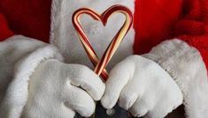 santa claus holding a candy cane in his hands with a heart shaped decoration on it