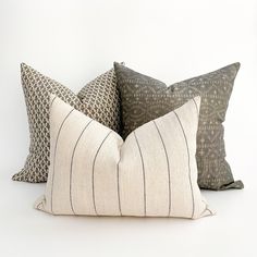 three pillows sitting next to each other on top of a white surface with black lines