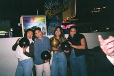 four girls are holding up their bowling balls and posing for the camera with each other