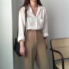 a woman standing in front of a chair with her hand on her hip and looking off to the side