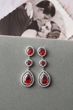 Vintage style  zircon  earrings  Colour: rhodium(silver tone) /clear/red Measurements: approx 5.1 cm x 16 mm  including studs(medium size not very long).  Materials:  rhodium over brass components, zircon crystals . Stud earrings. Great for wedding or other celebration. Same style with clear crystals: https://www.etsy.com/uk/listing/642610631/bridal-earringsart-deco-earrings-crystal?ref=listing-shop-header-0 MORE SAME STYLE: https://www.etsy.com/uk/shop/BridalArtDeco?ref=listing-shop-header-item Red Chandelier Drop Earrings For Wedding, Red Teardrop Chandelier Earrings For Wedding, Red Teardrop Crystal Earrings For Wedding, Red Pear-shaped Wedding Earrings, Red Chandelier Earrings For Anniversary, Red Sterling Silver Earrings For Wedding, Red Drop Earrings For Wedding, Red Crystal Drop Earrings For Wedding, Elegant Red Cubic Zirconia Bridal Earrings