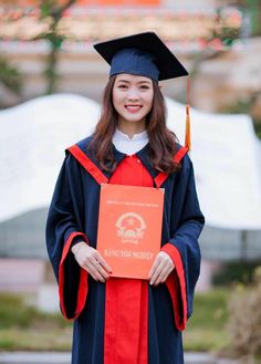 a woman in graduation gown holding up an orange sign