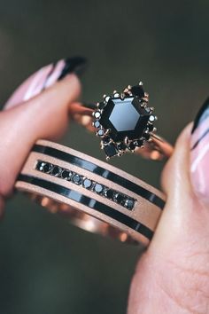 a woman holding two rings with black diamonds on them