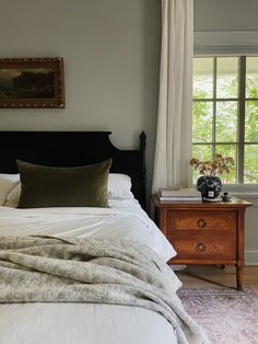 a bedroom with a bed, nightstand and window