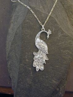 "This Peacock Bird pendant is Sterling Silver. The included chain is a Sterling Silver Figaro 50 chain. You may choose 16, 18 or 20 inch at the same price. Other length available at sightly higher prices. This Peacock Bird pendant measures 2 3/8\" tall by 7/8\" across. I hand cast all my pieces using the lost wax casting method. Please ask your needs. You may call me with questions, often I am out so please use my machine. 831-476-3176. Satisfaction Guaranteed! I send items USPS First Class unle Elegant Peacock Design Necklace For Gift, Elegant Peacock Pendant Necklace, Elegant Silver Jewelry With Peacock Design, Elegant Peacock Color Pendant Necklace, Sterling Silver Necklace With Peacock Design, Silver Peacock Pendant Necklace, Elegant Silver Necklace With Peacock Design, Elegant Peacock Color Pendant Jewelry, Peacock Design Pendant Necklace Gift