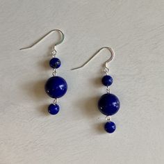 These earrings are made of sterling silver wire and two sizes of round Lapis Lazuli stones. Measuring two (2) inches long, these earrings are a nice addition to any outfit. The sterling silver ear hooks on these earrings are perfect for even the most sensitive ears. These earrings make a great gift and gift wrapping comes standard with any purchase. A little bit about the gemstone used in this piece: Lapis Lazuli encourages self-awareness, allows self-expression and reveals inner truth, providin Adjustable Lapis Lazuli Earrings As Gift, Adjustable Lapis Lazuli Earrings For Gift, Handmade Round Lapis Lazuli Earrings, Lapis Lazuli Dangle Earrings With Natural Stones, Lapis Lazuli Dangle Earrings For Pierced Ears, Pierced Lapis Lazuli Round Jewelry, Sterling Silver Drop Earrings With Natural Stones, Lapis Lazuli Natural Stones Drop Earrings, Sterling Silver Earrings With Natural Stones