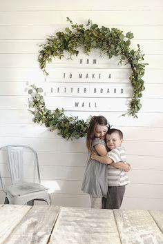 two children hugging each other in front of a sign that says, mom 10 make a letterboard wall