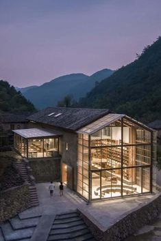 the building is lit up at night with stairs leading up to it and people walking around