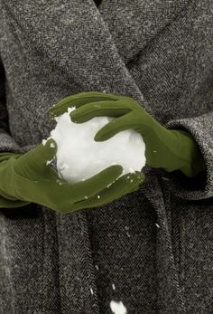 a person wearing a coat and holding a piece of green leaf with white powder on it