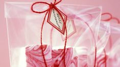 a package with red string wrapped around it on top of a pink tablecloth covered surface