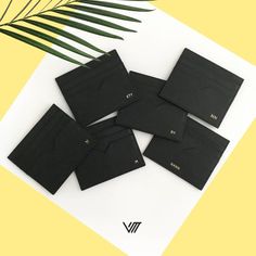 six black envelopes with gold foil on top and palm leaves next to them in front of a yellow background