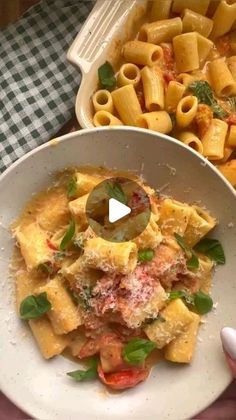 a white bowl filled with pasta next to a casserole dish on a checkered table cloth