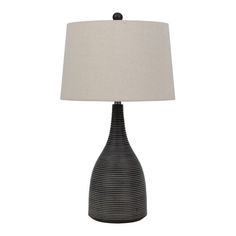 a black and white table lamp with a beige shade on the top, in front of a white background