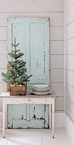 a small christmas tree sitting on top of a white table next to a blue door