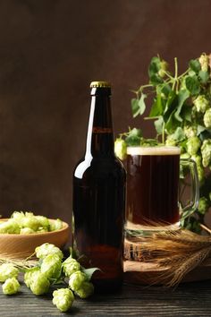 a bottle of beer next to a bowl of hops