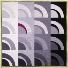 a quilted wall hanging made with black, grey and white circles on the front