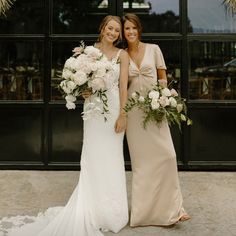 two women standing next to each other holding bouquets