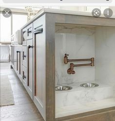 an open cabinet in the middle of a kitchen with two sinks and three faucets