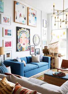 a living room with blue couches and pictures on the wall above them in front of a large window