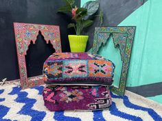 two colorful rugs and a green vase sitting on top of each other