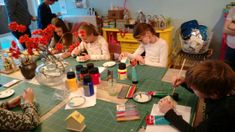 several people sitting around a table with craft supplies on it while others look at them