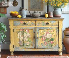 a yellow painted cabinet with flowers and fruit on top