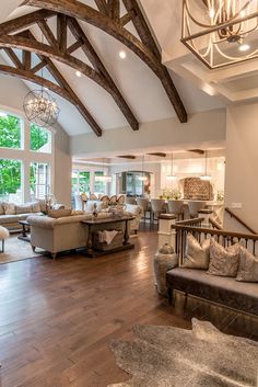 a living room filled with lots of furniture and wooden beams on the ceiling, along with large windows