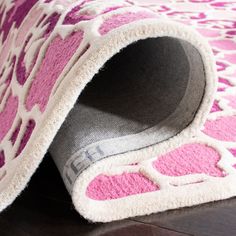 a pink and white animal print rug on the floor with it's end rolled up