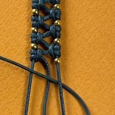 a close up of a pair of scissors on a yellow wall with black cords and gold beads