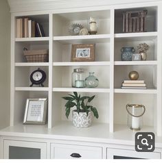 a white bookcase filled with lots of books next to a clock and other items