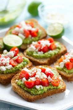 several pieces of bread with avocado and tomatoes on them sitting on a white plate