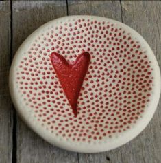 a white plate with a red heart painted on the front and bottom, sitting on a wooden surface