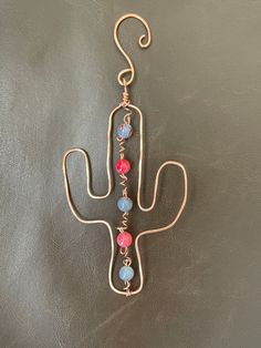 a pair of earrings hanging from a hook on a leather surface with the shape of a cactus