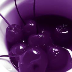 a bowl filled with purple cherries sitting on top of a table