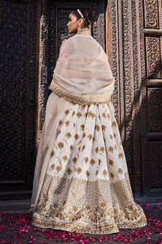 Ivory silk lehenga with an attached cancan and gold floral embroidery. Comes with a padded blouse and a dupatta.
Components: 3
Pattern: Embroidered
Type Of Work: Floral
Neckline: Deep V Neck
Sleeve Type: Sleeveless
Fabric: Silk
Color: Ivory
Other Details: 
Attached lining
Product Weight: 2 Kgs
Occasion: Wedding - Aza Fashions Padded Blouse, Ivory Silk, Silk Lehenga, Fabric Silk, Set Women, Gold Floral, Embroidered Silk, Color Ivory, Deep V Neck