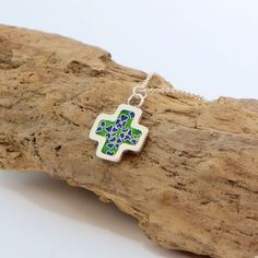 Every piece of our jewellery is entirely handmade in our small, family workshop situated in a tiny, thatched cottage in a beautiful Killarney, co. Kerry. This blue and green enamelled silver cross pendant is made with fine silver and decorated with vitreous enamel called cloisonné. It is hanged on sterling silver chain with lobster clasp. Dimension of the cross: 2.8 cm x 2.2 cm Weight: 5.5 g Sterling Silver chain length is 45cm plus 3 cm chain extension. Cloisonné or Vitreous Enamel is an intric Handmade Small Green Jewelry, Small Handmade Green Jewelry, Sterling Silver Jewelry With Green Inlay, Handmade Blue-green Jewelry Gift, Hand Painted Blue Sterling Silver Necklace, Green Inlay Necklace As Gift, Handmade Green Enamel Necklaces, Handmade Blue-green Necklaces For Gifts, Handmade Blue-green Necklace For Gift