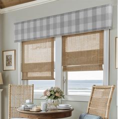 two chairs and a table in front of a window with roman shades on the windowsill