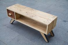 a wooden table sitting on top of a sidewalk next to a brick floor with an open drawer