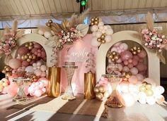 a table topped with balloons and vases filled with pink, gold and white flowers