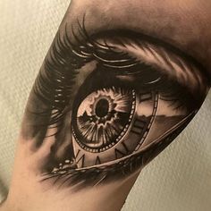 an eye tattoo on the arm that has a clock in it's irise