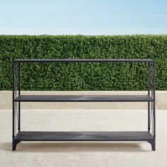 a black shelf sitting in front of a hedge