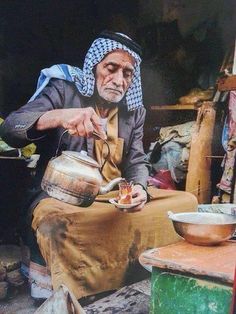 an old man is sitting down and pouring something into a bowl with a spoon in his hand