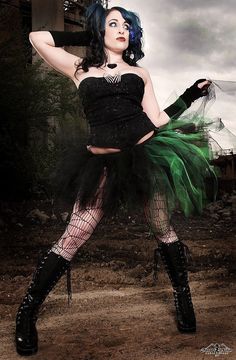 a woman dressed in black and green is posing