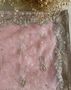 a pink cloth with silver sequins and beads on it next to dried flowers