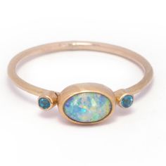 A captivating Australian boulder pipe opal with a vibrant overall aqua hue that displays gorgeous flashes of electric green and lilac.  Measuring 8.3 x 5.6 mm this 0.75 carat rainbow beauty is bezel set in 14k yellow gold with a sterling silver back. A duo of 2 mm faceted apatite gemstones add a playful pop of color an Oval Blue Opal Ring In 14k Gold, Laos Jewelry, Green And Periwinkle, Rainbow Beauty, Dream Future, Electric Green, Stacking Bands, Australian Boulder Opal, Opal Ring