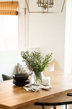 a wooden table topped with plates and vase filled with flowers