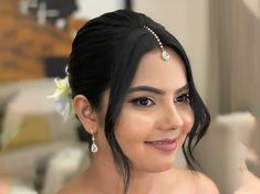 a woman with black hair wearing a tiara and pearls on her head, smiling at the camera