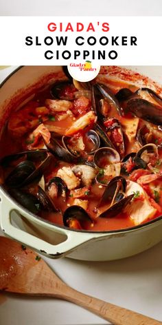 a pot filled with clams and sauce on top of a white counter next to a wooden spoon